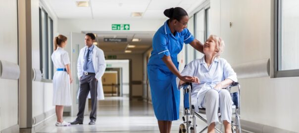 Senior Female Patient in Wheelchair & Nurse in Hospital