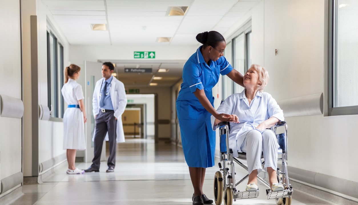 Senior Female Patient in Wheelchair & Nurse in Hospital